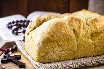 homemade bread made in the Easter and Eucharist period, called Christ bread, religious symbol, with Bible and crucifix in the background