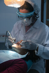 Odontologia avanzada, cuidados confiables. Joven paciente afro-americano en una clinica dentista realizando una limpieza bucal . Dentista examinando los dientes del paciente en una clinica profesional - obrazy, fototapety, plakaty