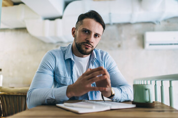 Fototapeta premium Thoughtful young man sitting in cafe while having break between University lessons