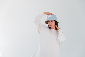 Sports girl in white logo sweatshirt. Woman in denim hat