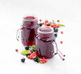 Drink infusion berry decoction of fresh red and black currants in a glass jar with a bamboo straw on a light background