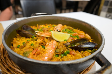 The famous traditional fish dish of spanish food and catalan cuisine - seafood paella with shrimps, mussels, fish, rice, lemon and herbs