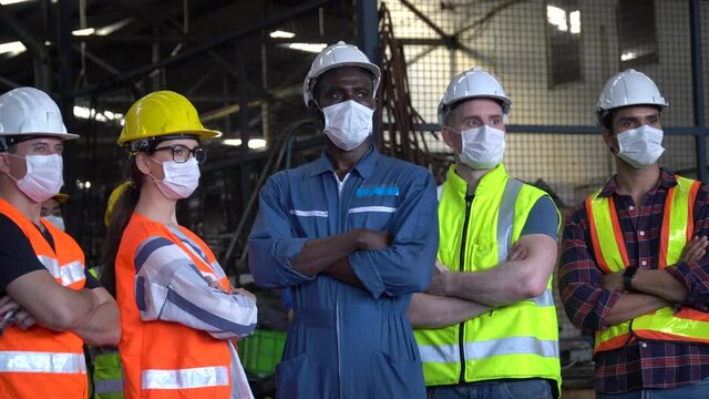 group of professional factory workers wear protective face mask  standing and crossed arms in industrial factory protect for pollution and fight corona virus pandemic or covid 19 outbreak. zoom out