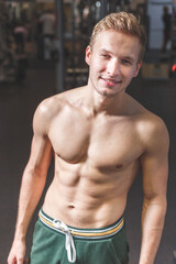 Fototapeta na wymiar Sexy portrait of a young muscular male model with great happy smile in the gym