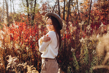 Portrait of a girl in a hat in an autumn park, a woman walks in the woods at sunset