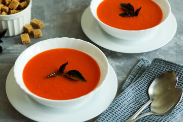 Tomato soup in bowls on gray concrete background