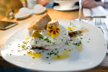 A traditional appetizer, snack or tapas from Spanish cuisine and Catalan food - baked eggplant served with white cheese (sour cream) and crispy toasted bread in the restaurant of Barcelona, Spain