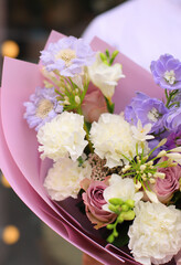 Strong man holding a delicate bouquet of beautiful flowers in his hands. Delicate flower bouquet. Fresh beautiful flower.