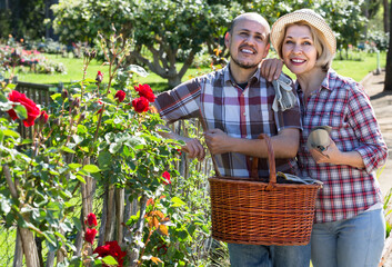 portrait of a smiling russian adult couple taking care of green plants in the garden