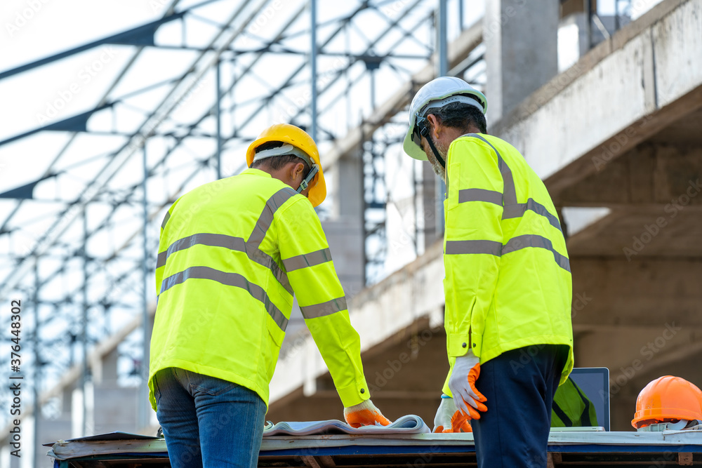 Aufkleber engineers discussion with architect about detail of building at construction site.