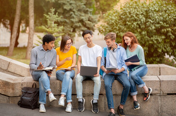 Fototapeta premium Chinese Student Showing Educational Website On Laptop To Coursemates Outside