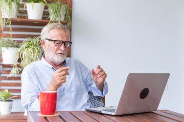 Senior retirement man is working with his laptop at home feeling unhappy