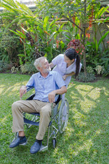 A nurse take care a senior male on wheelchair in his garden at home