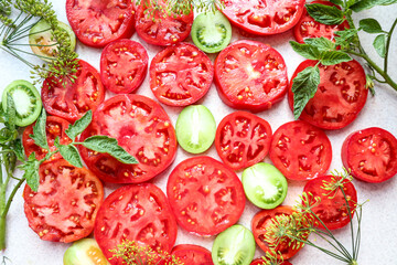 Red tomato slices with green ones on a gray background with dill branches, close-up, top view