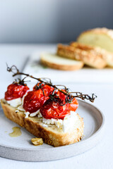 Tomato confit and goat cheese bruschetta on grey concrete table. Selective focus
