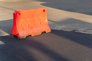 Orange Plastic block restricting the passage of cars during repair work. Safe Plastic Road Fence.
