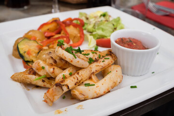 Delicious seafood restaurant dish from French cuisine - stewed calamari served with tomato and orange salsa and vegetable ratatouille