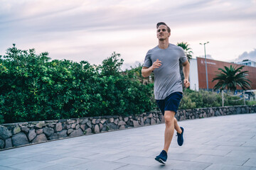 Handsome determined active male jogger enjoying energy and power during cardio training keeping...