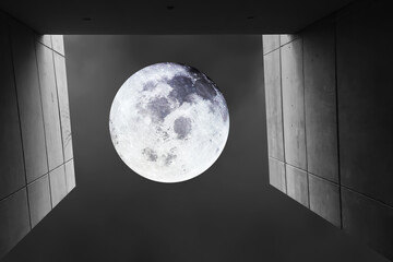Looking up seeing image of bright and shiny full moon with dark sky background and perspective of height concrete wall on midnight time. Image of moon furnished by NASA.