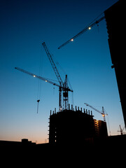 Construction crane at sunset time on the blue sky with no clouds. Residential buildings construction at evening time minimalistic photo