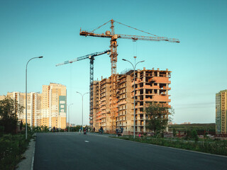 Construction crane building multystory residential building at evening time