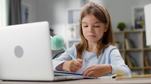 The girl writes in a notebook. Distance learning, school online.