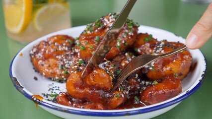 Close up of cutting cauliflower in sticky sweet and sour sauce. Vegan Asian cuisine. 