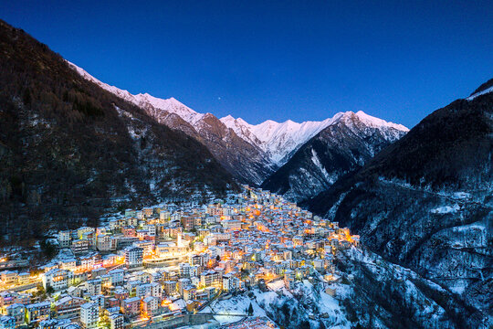 View by drone of winter dusk over the illuminated village of Premana, Valsassina, Lecco province, Lombardy 