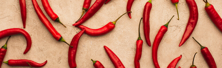 top view of scattered chili peppers on beige concrete surface, panoramic shot