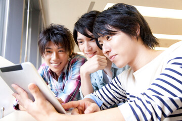 タブレットPCを見る男子大学生 © Paylessimages