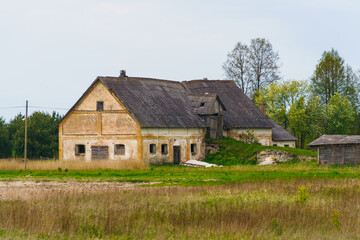 Fototapeta na wymiar Very old abandoned agricultural buildings of the 19th century in a Latvian village, May 2020.
