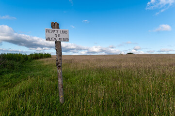 wooden sign on a meadow. The sign says 'Private Land, no Walking'