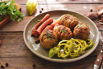 Baked potatoes with carrots. Gray plate. Wooden background. Delicious and healthy lunch. Hasselback potatoes.