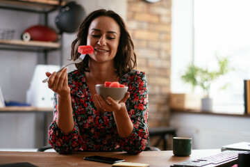 Businesswoman in office having healthy snack. Young businesswoman eating fruit while working.