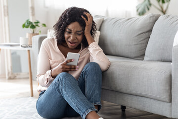 Bad News. Upset Shocked African Woman Reading Message On Smartphone At Home