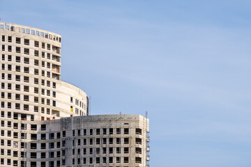 Fototapeta premium View of a modern complex of unfinished monolithic concrete buildings against the sky. Global urban development concept. Copy space. High quality photo