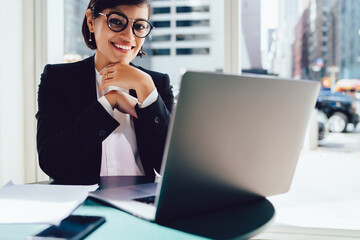 Smiling woman in glasses with laptop in modern workplace