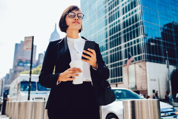 Elegant businesswoman with smartphone and coffee - Powered by Adobe