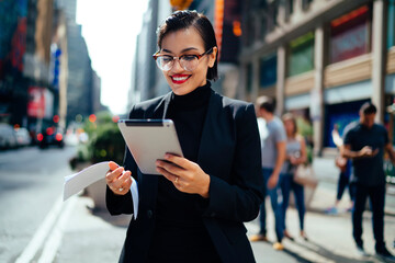 Cheerful businesswoman with tablet on avenue