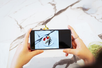 hand hold smartphone taking a photo of dessert.