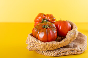 Basket with a red heirloom tomatoes and yellow background
