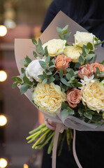 Magnificent rustic bouquet of tulips, roses and other flowers and herbs. Young woman holding rustic beautiful bouquet of interesting flowers.
