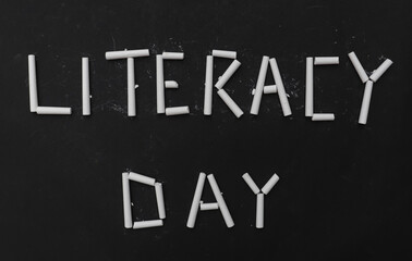 Literacy Day Written with White Chalk Pieces on Black Background