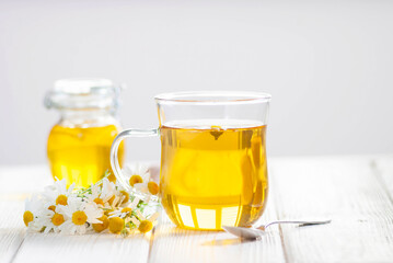 Cup of herbal tea with chamomile flowers and honey on the white wooden background. Natural organic alternative medicine