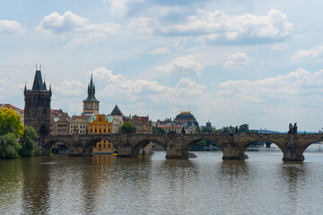 old stone tower on Charles Bridge from 1402 and old architecture and blue sky in the background in the center of Prague in the Czech Republic next to the Vltava River