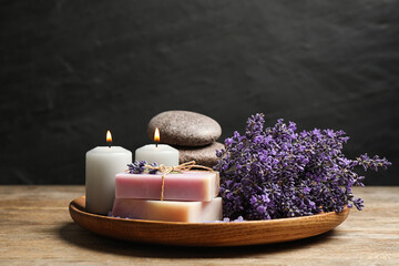 Obraz na płótnie Canvas Burning candles, stones, soap bars and lavender flowers on wooden table