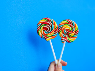 colorful lollipop in hand on blue background