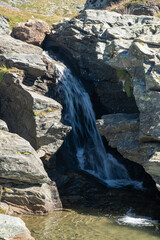 Panoramic view of alpine landscape with a small waterfall.