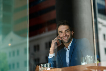 Smiling businessman talking on his cellphone inside of a cafe