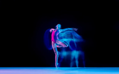 Smoke. Young and graceful ballet dancer on black studio background in neon mixed light. Art, motion, action, flexibility, inspiration concept. Flexible caucasian ballet dancer, weightless jumps.